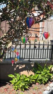 Solar-powered hot air balloon lights hanging in a garden.