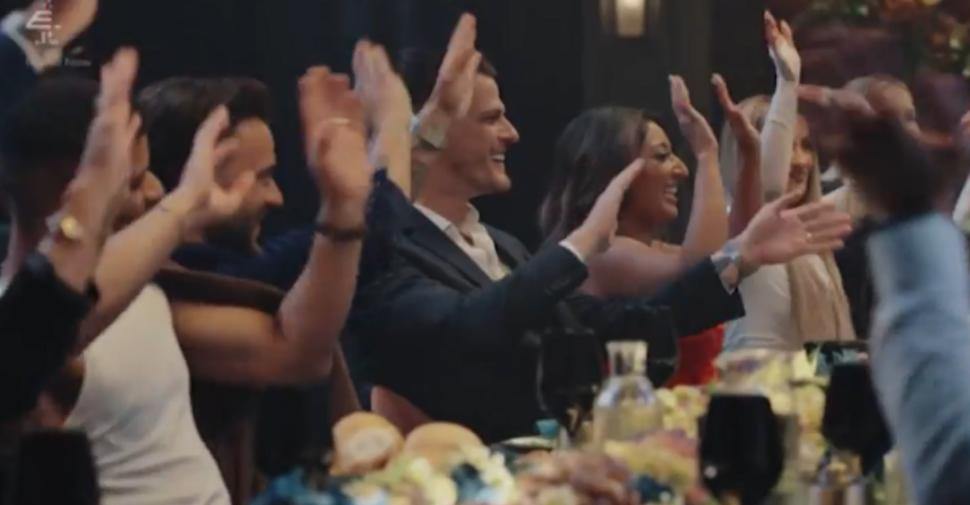 Attendees clapping and smiling at a formal event.