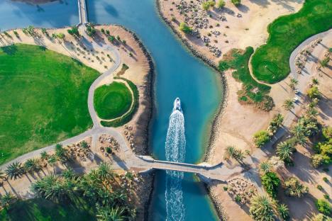 Aerial view of a golf course with a boat on a waterway.