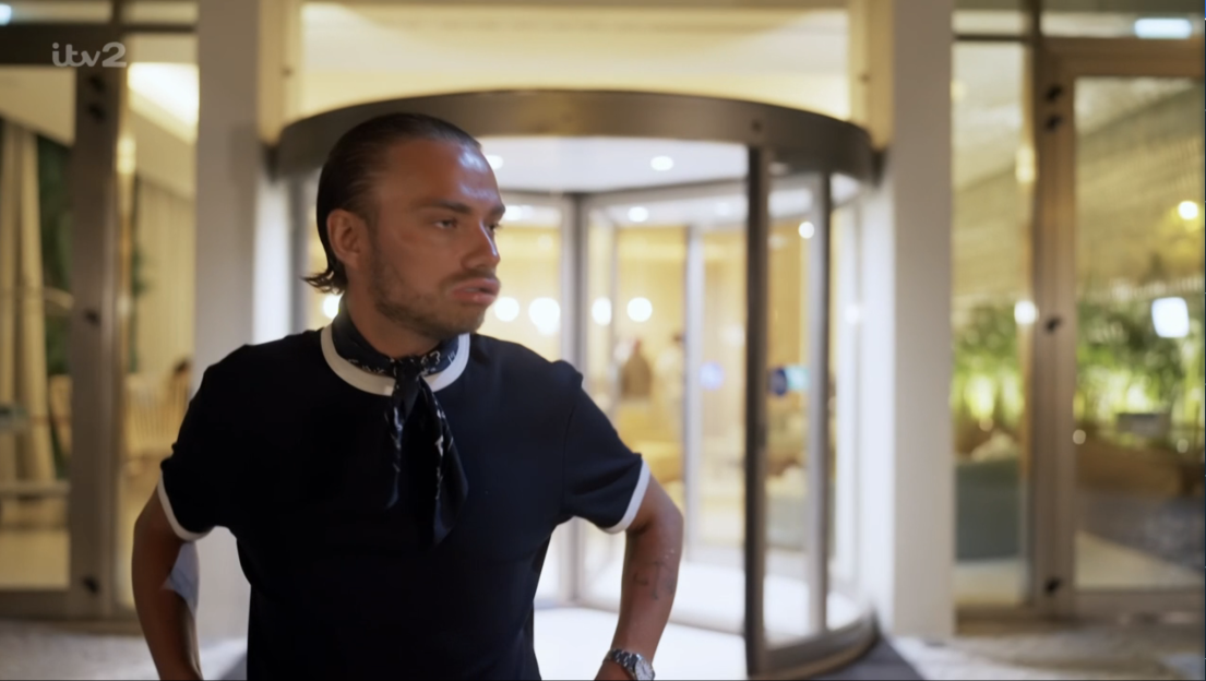 Screenshot of a man standing in front of a revolving door.