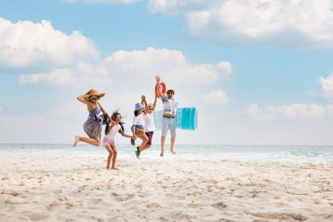 Happy Asian family jumping on a beach.
