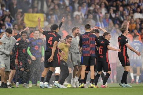 Barcelona players celebrating a football match victory in the rain.