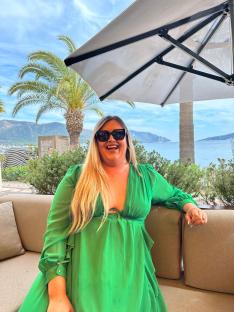 Woman in green dress smiling outdoors.