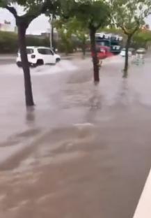 Flooded street in Majorca, Spain, with a car driving through the water.