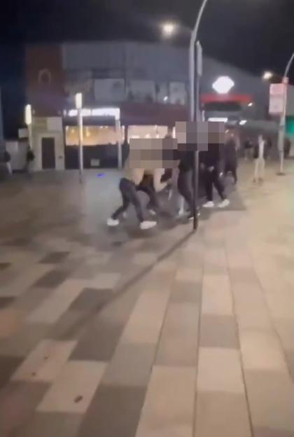 A group of people involved in a street brawl at night.
