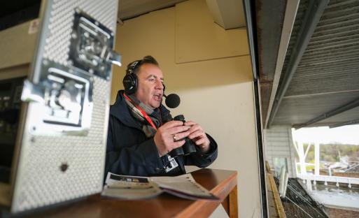 John Hunt, BBC racing commentator, in a booth at a racetrack.