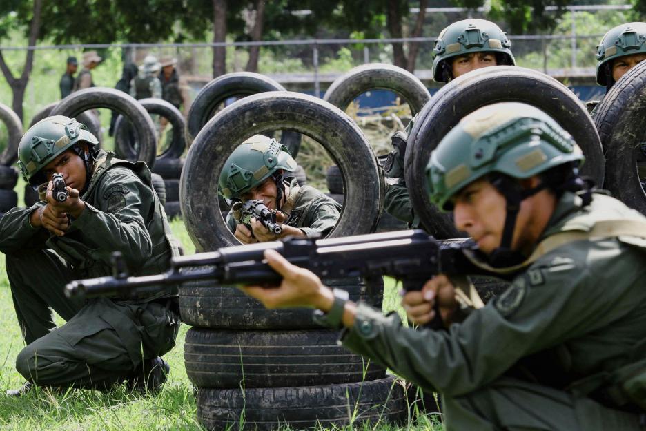 Soldiers training with rifles behind tire barricades.