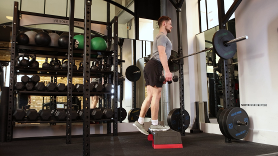 Man performing a single-leg dumbbell exercise in a gym.