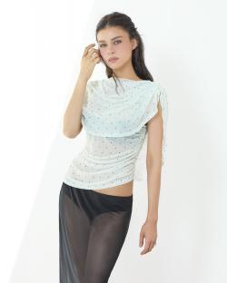 Nicola Peltz Beckham modeling a white polka dot top and sheer black skirt for NA-KD.
