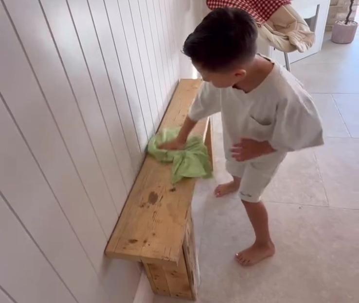 Boy cleaning a wooden bench.