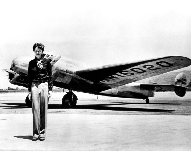 Amelia Earhart stands in front of the Lockheed Electra airplane in which she disappeared.