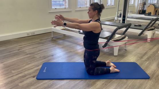 Woman doing Pilates leg exercise with resistance band.