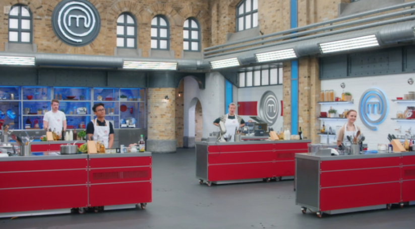 Four MasterChef contestants stand at their cooking stations in the MasterChef kitchen.