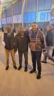 Man posing with friends outside a stadium.