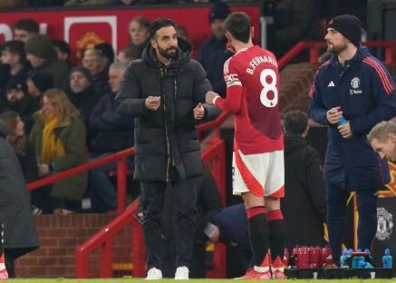 Ruben Amorim, manager of Manchester United, speaking with Bruno Fernandes during a Premier League match.