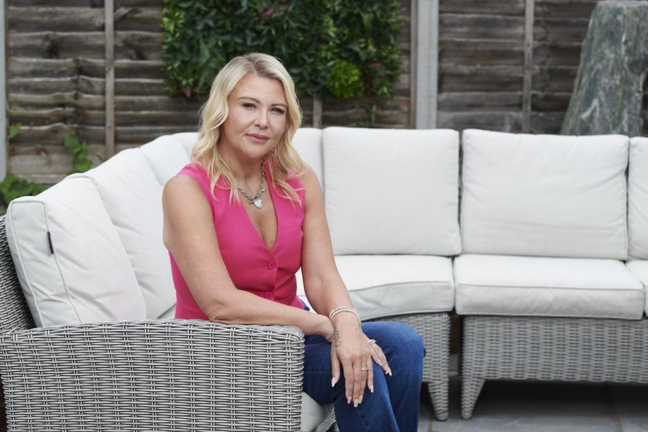 Woman in pink vest sitting on patio furniture.