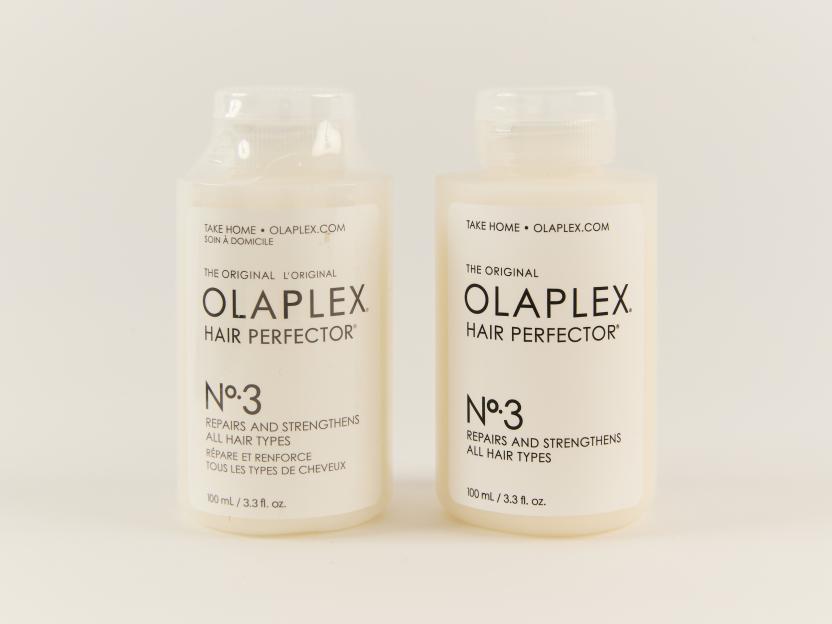 Two white bottles of Olaplex No. 3 Hair Perfector, one with a plastic-sealed cap and the other without.
