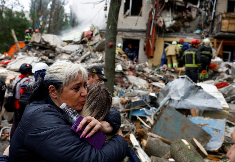 A woman embraces another person amidst the rubble of a bombed building in Kyiv, Ukraine.