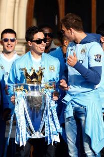 Manchester City players celebrating with the Premier League trophy.