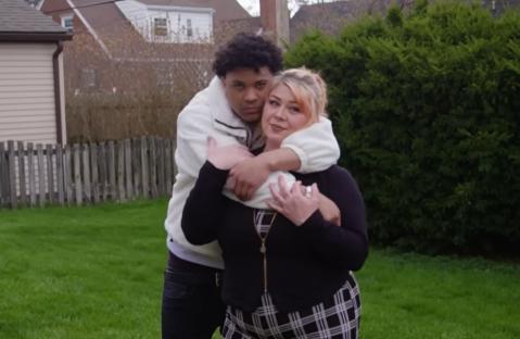 A young man and a woman embracing in a backyard.