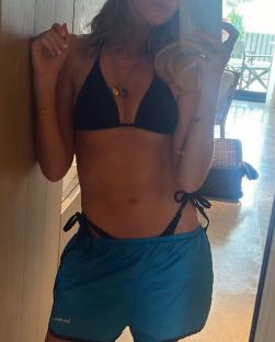Charley Webb in a black bikini and teal shorts.