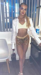 Young woman in sequined shorts and white shirt.