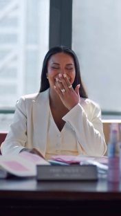 A woman laughing while sitting at a desk.