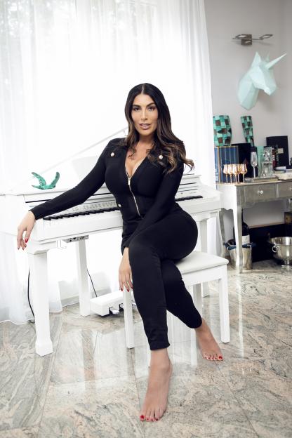 Ava Koxxx, Britain's tallest porn star, sitting at a white piano.