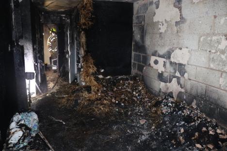 Fire damage inside a building, with a firefighter visible in the background.