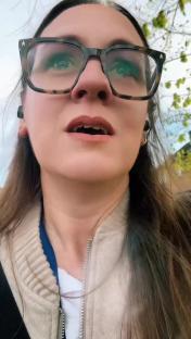 Woman wearing glasses and earbuds, speaking.