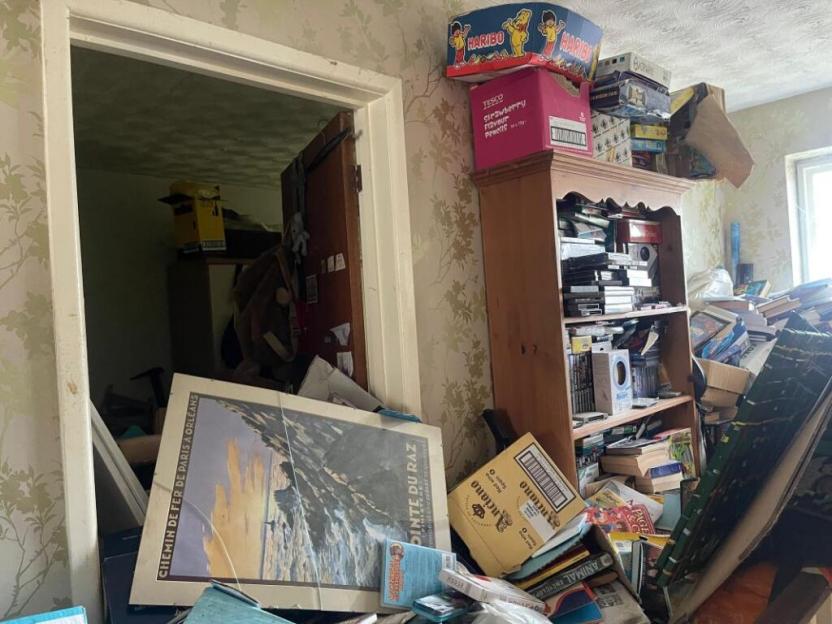A cluttered room filled with books, boxes, and other items.
