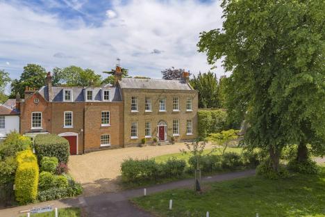 Aerial view of a large brick house with a red door.