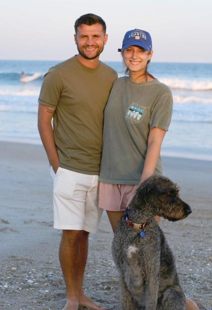 A couple and their dog on a beach.