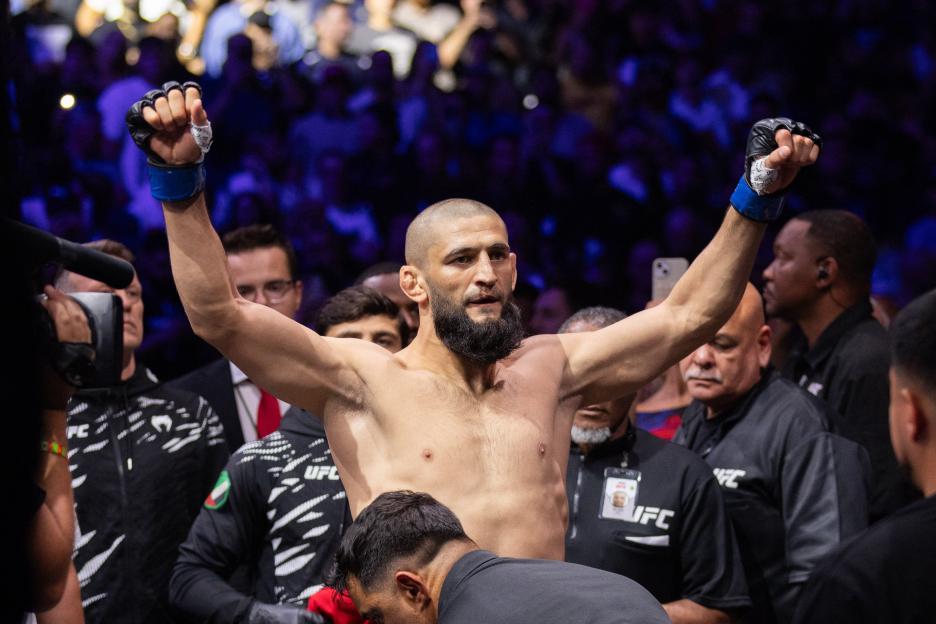 Khamzat Chimaev with arms raised in victory at a UFC event.