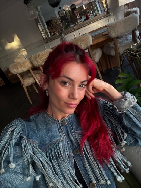Woman with red hair wearing a fringed denim jacket.