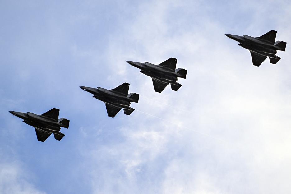 Four Lockheed Martin F-35B jets flying in formation against a partly cloudy sky.