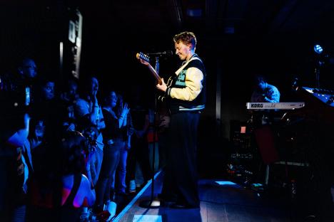 La Roux performing on stage with a guitar.