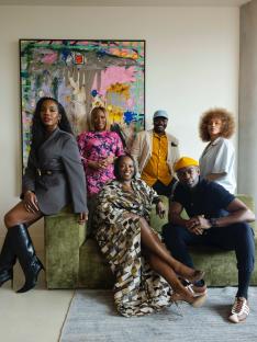 Group photo of six people posing on and around a green couch in front of an abstract painting.