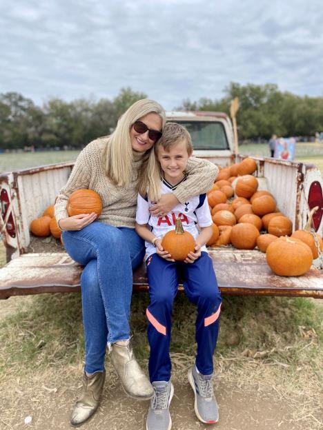 Woman and child with pumpkins in the back of an old truck.