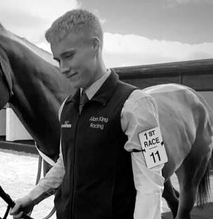 Black and white photo of a young jockey with a horse.