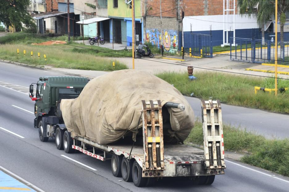 Truck transporting a covered military tank.