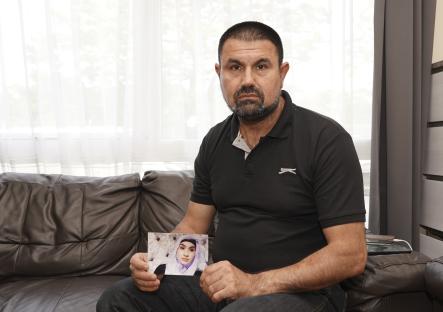 A father holding a photograph of his deceased daughter.