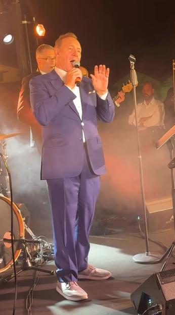 Kevin Spacey singing on stage with a band.