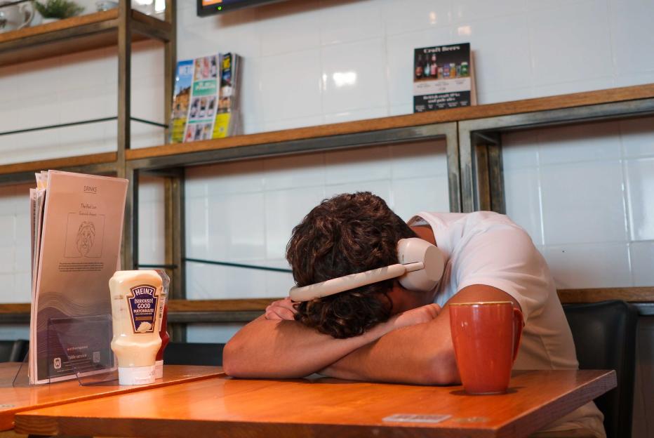 Man sleeping on table at a pub with headphones on.