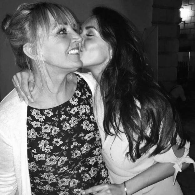 Black and white photo of a daughter kissing her mother on the cheek.