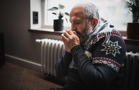 Man warming hands near radiator.
