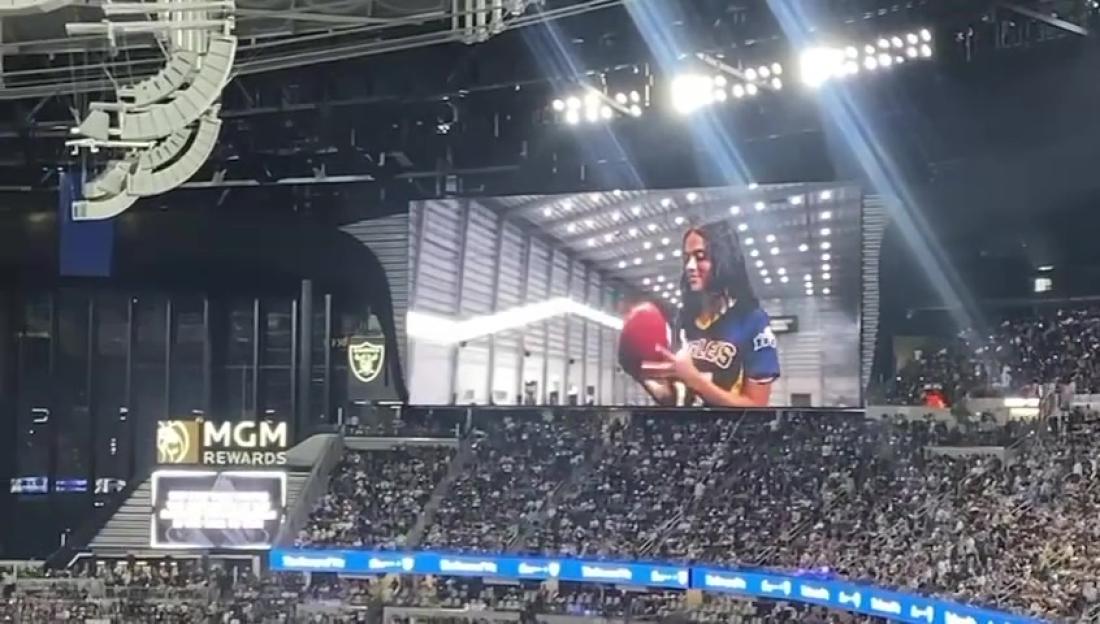 Video screen at a stadium showing a woman in a jersey holding a basketball.