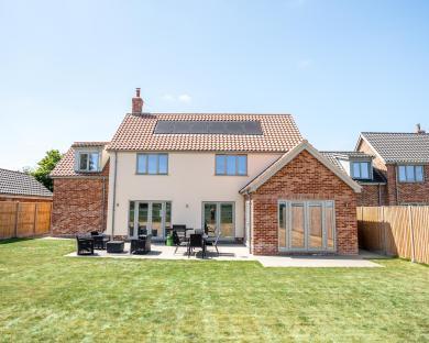 Rear view of a house with solar panels on the roof and patio furniture.