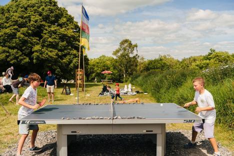 Two children playing table tennis outdoors.