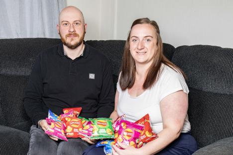 Couple holding bags of crisps after a hotel mishap.